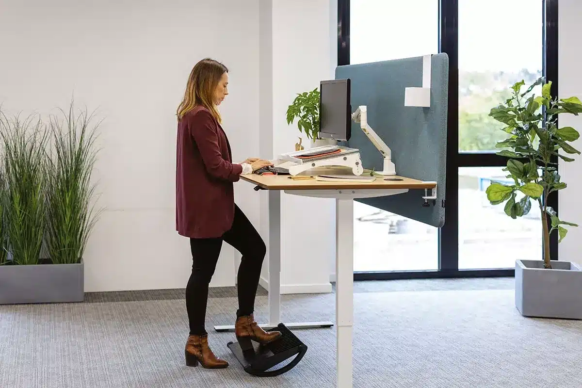 Femme utilisant un repose-pied de bureau pour une posture de travail ergonomique et saine.