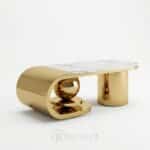Table basse design avec structure dorée sculpturale et plateau en céramique, idéale pour les espaces premium.