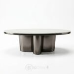 Table basse ovale contemporaine avec plateau en céramique et base sculpturale métallique.